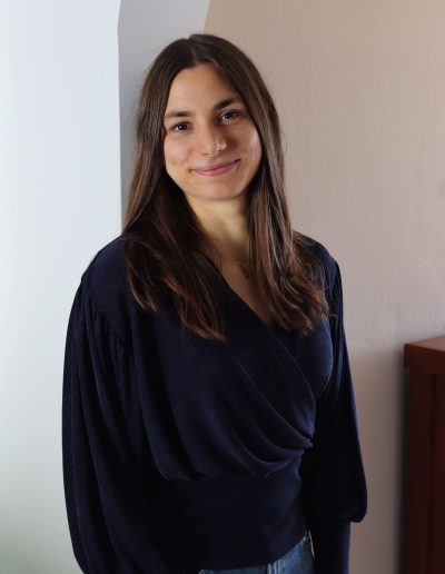 Alena, Webdesignerin für verkaufsstarke Websites, lehnt an einer Wand